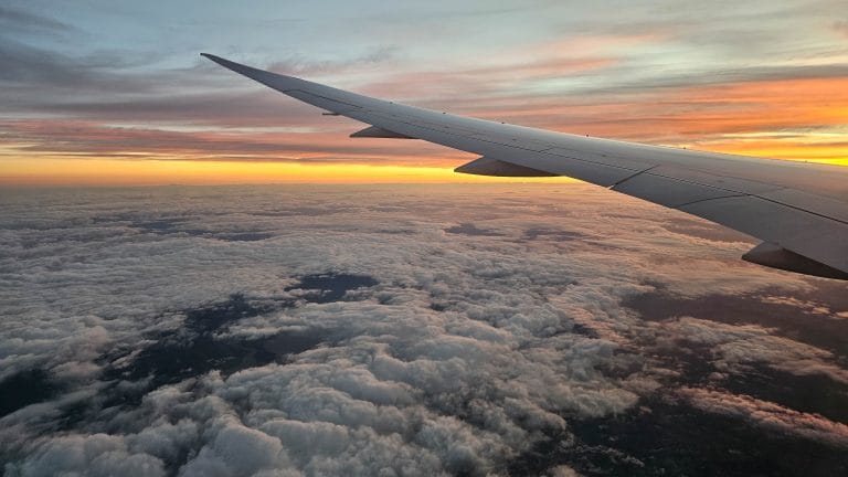 Plane wing above the clouds, during sunset