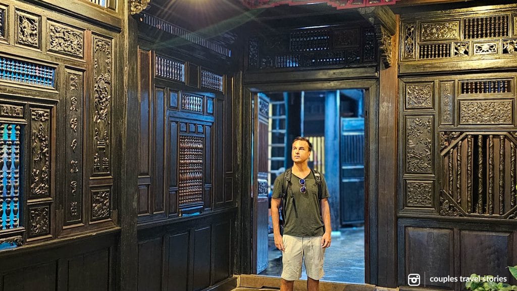 Man inside a traditional Vietnamese house with carved wood decorations in the Old Town, one of the things to do in Hoi An, Vietnam