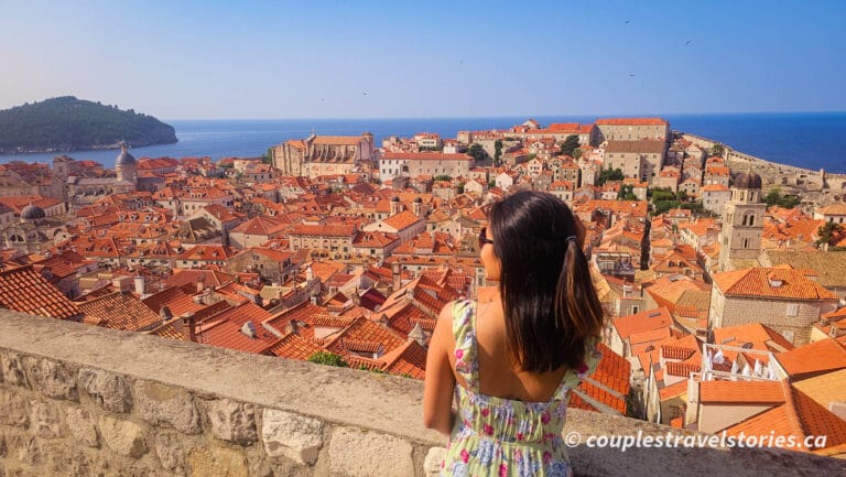 Woman standing on Dubrovnik city walls, looking down at the old town